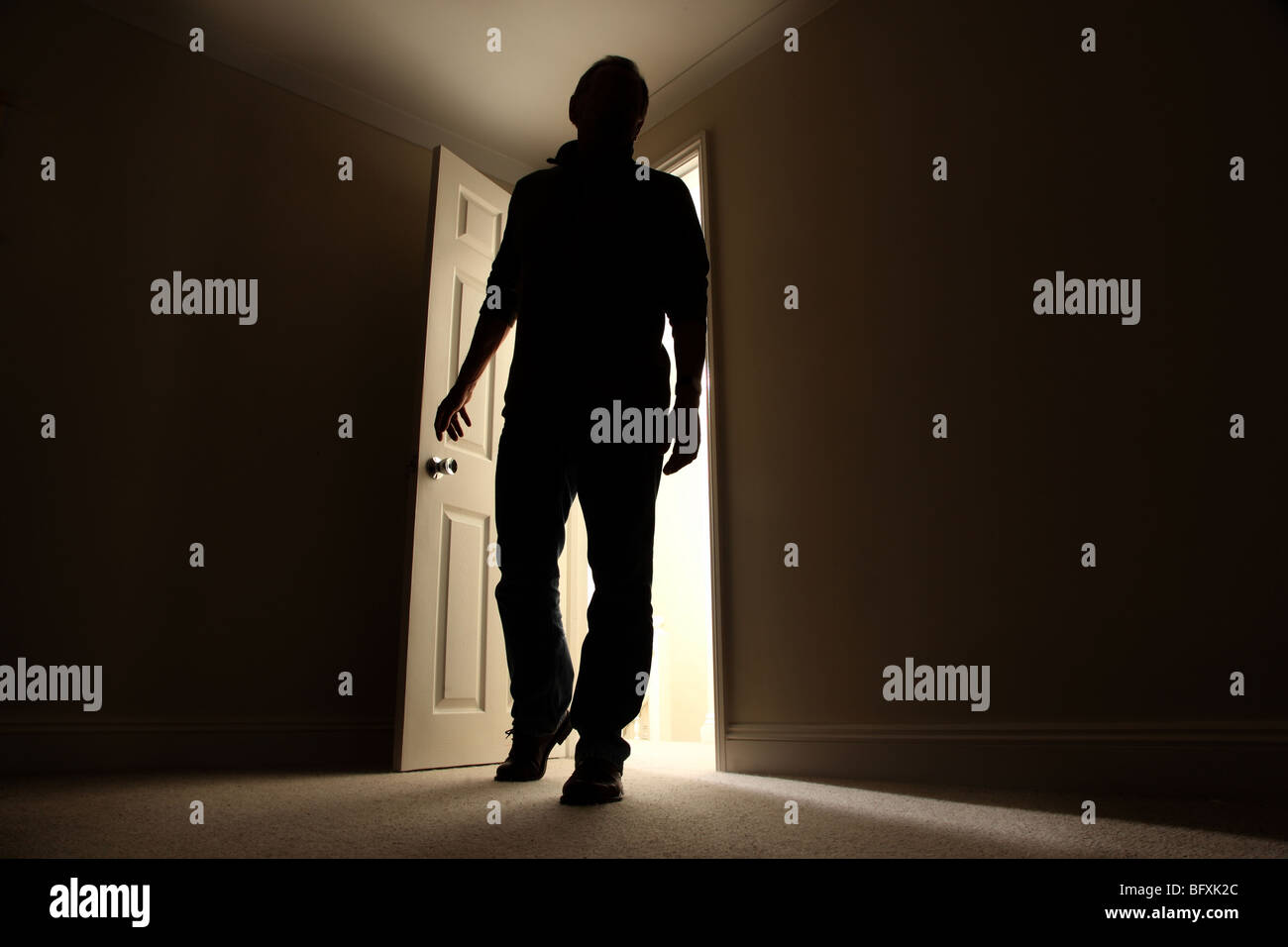 Silhouette eines Mannes in einem dunklen Raum mit einer Welle von Licht hinter Stockfoto