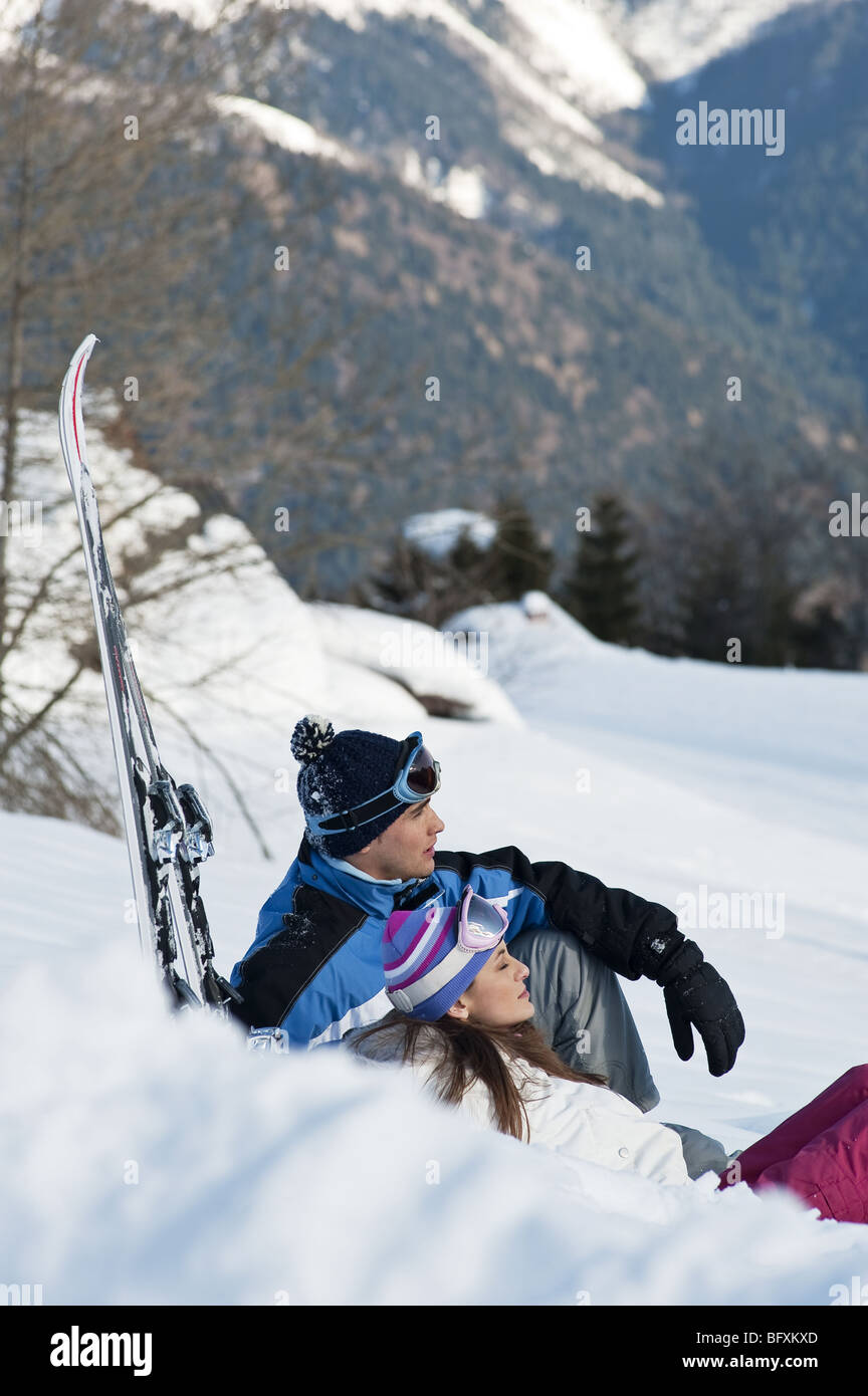 Paar, sitzen im Schnee mit Skiern Stockfoto