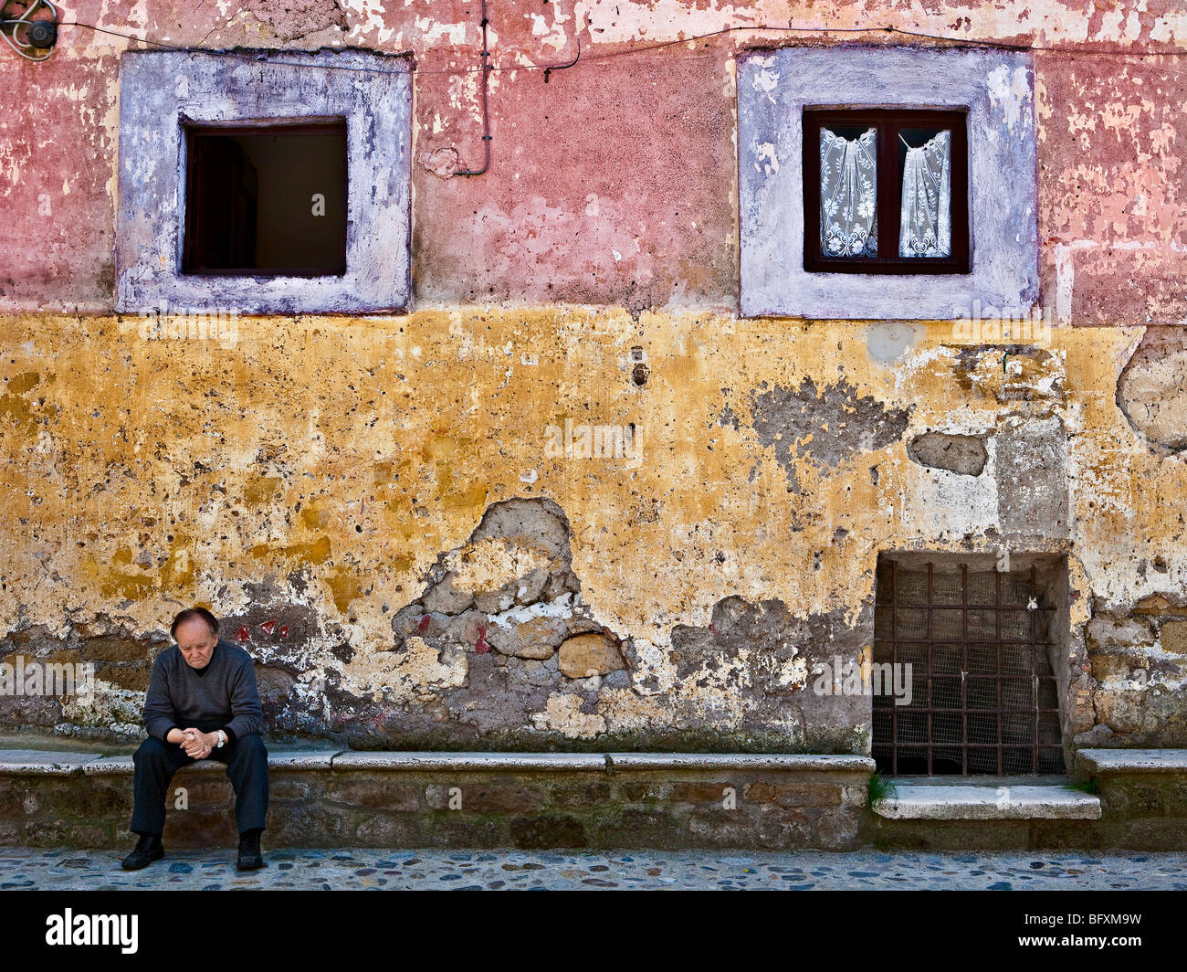 Mann, sitzen und denken, gegen eine alte Mauer. Calcata, Lazio Rom, Latium, Italien, Europa Stockfoto