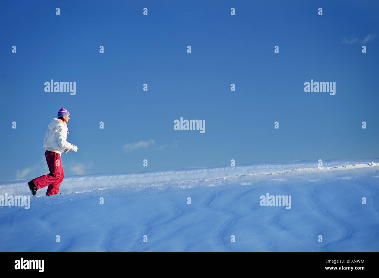 Junge Frau läuft im Schnee Stockfoto