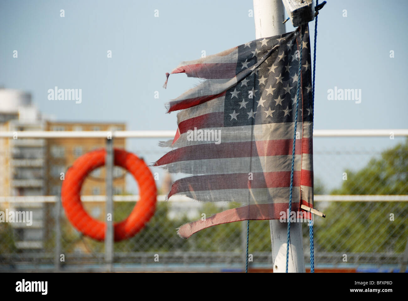US-Flagge in Fetzen mit einem Rettungsring im Hintergrund Stockfoto