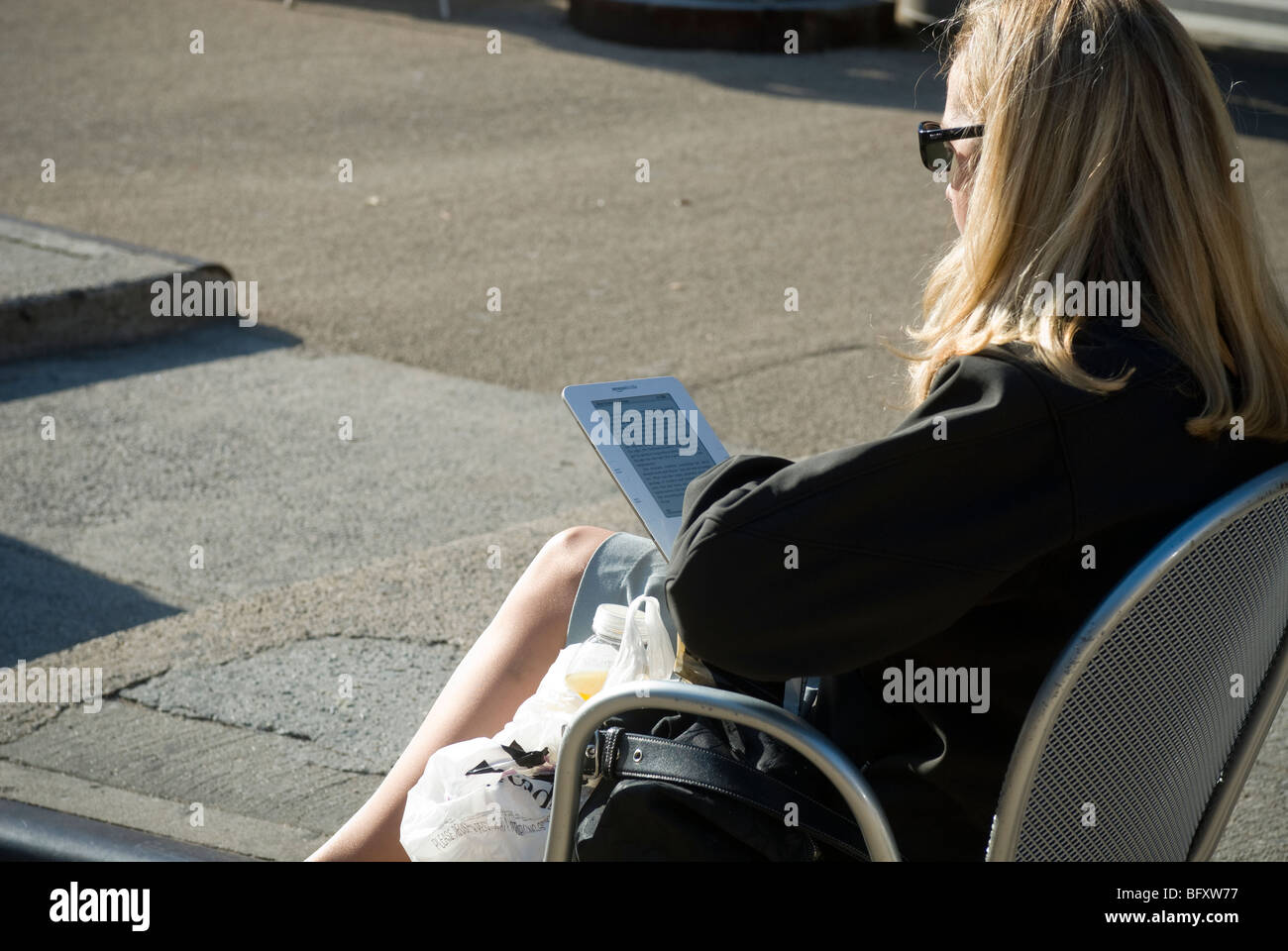 Ein Leser nutzt ihr Amazon Kindle e-Book auf der Straße vor Madison Square Park in New York Stockfoto