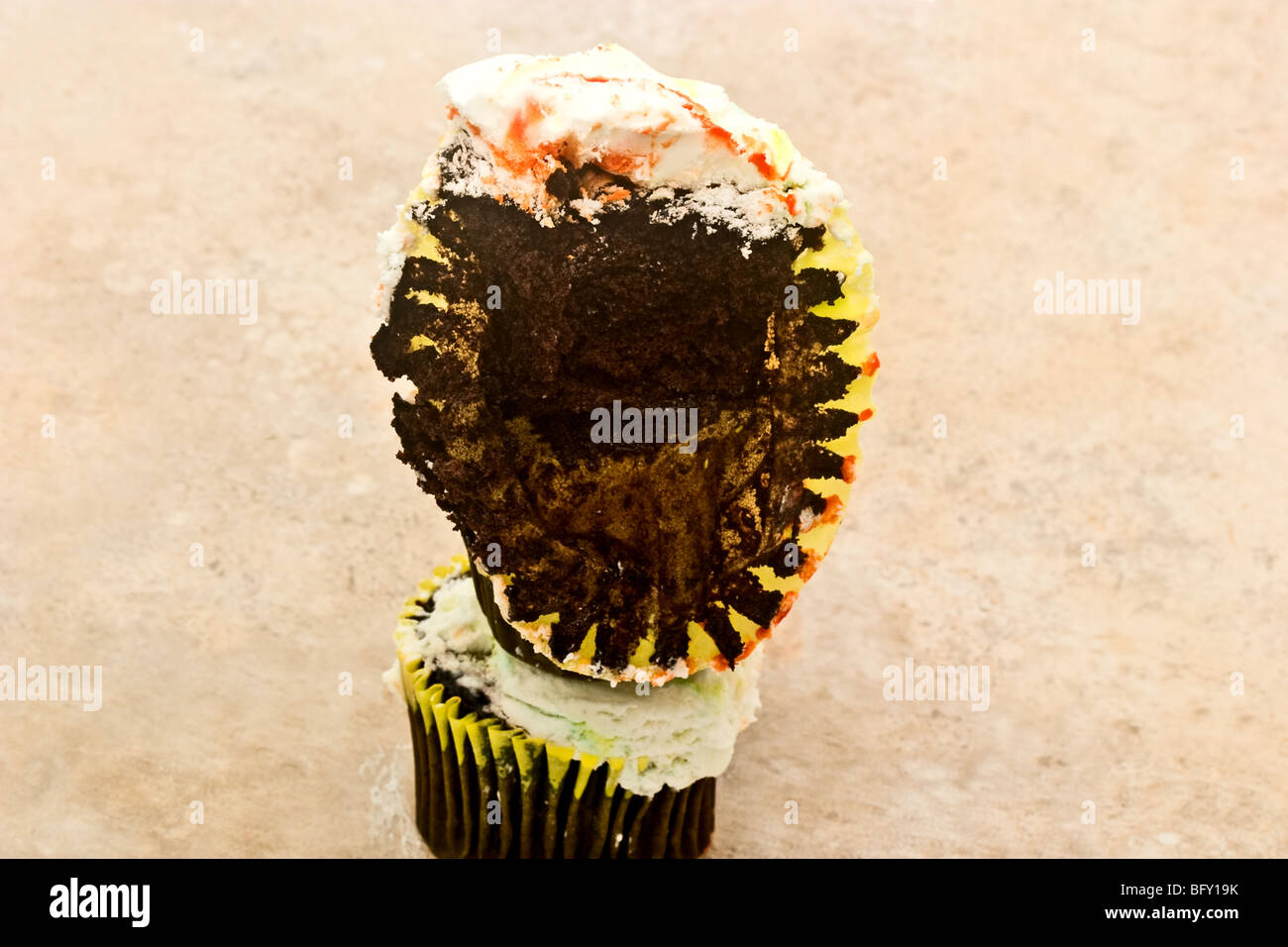 Stapel von drei Schokoladen Cupcakes bedeckt mit Puderzucker, einer halb gegessen Stockfoto