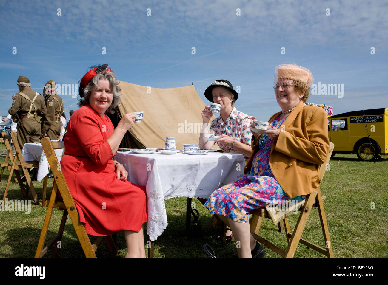 Drei reifere Damen, die in den vierziger Jahren gekleidet waren, hatten Tee. Rafa Airshow, Shoreham Airport, Sussex, England Stockfoto