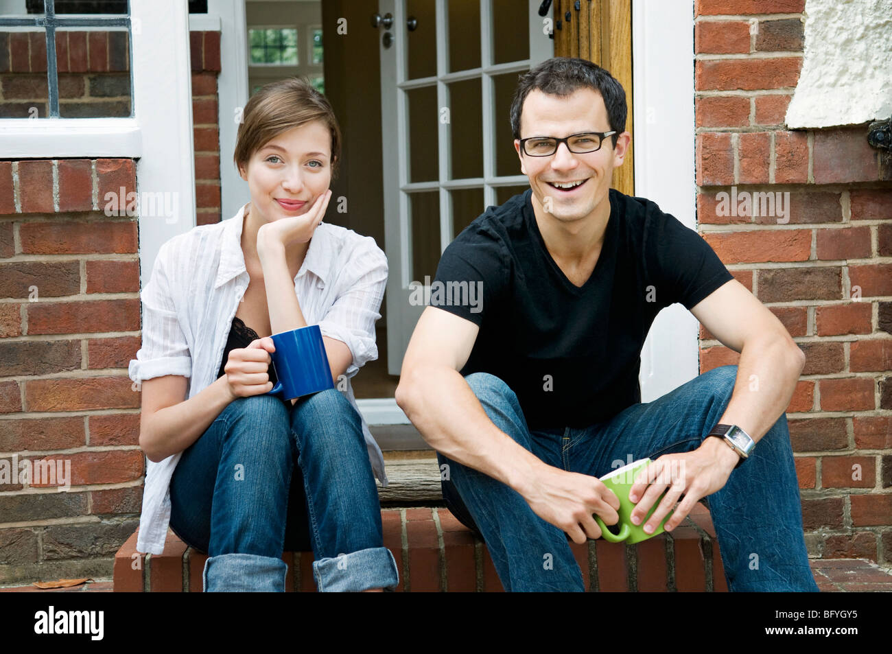 Ein junges Paar sitzt vor ihrer Haustür Stockfoto