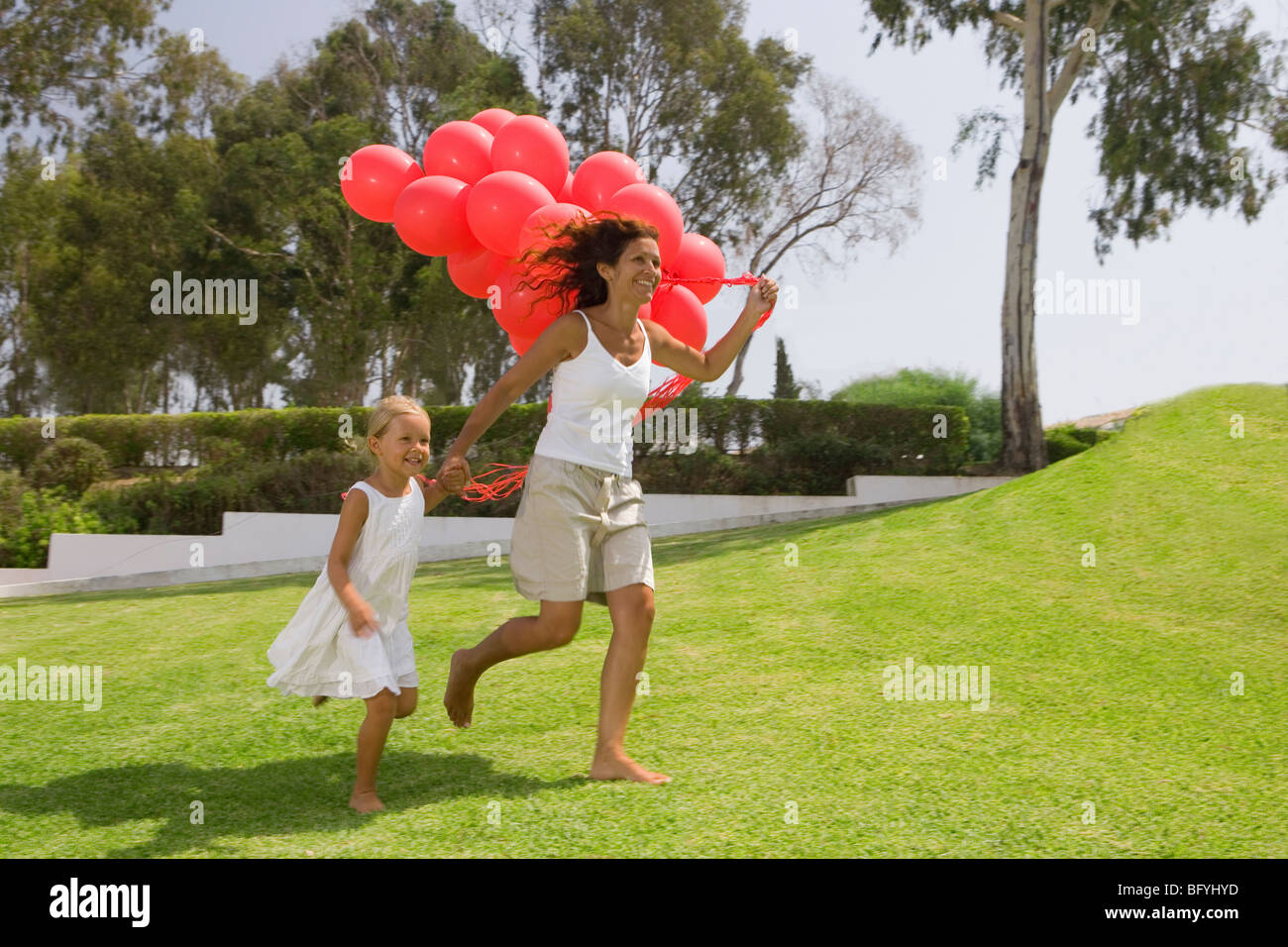 Mädchen und Mutter läuft mit Luftballons Stockfoto