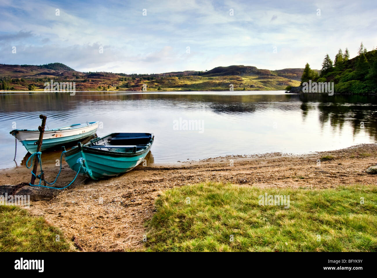 Die entfernten Loch Ordie, nr Dunkeld, Schottland, aufgenommen kurz nach Sonnenaufgang mit zwei alten Ruderboote im Vordergrund Stockfoto