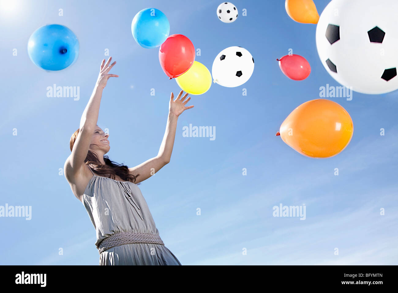junge Frau, die Ballons in den Himmel fliegen zu lassen Stockfoto