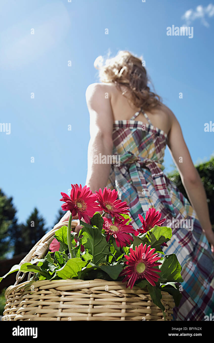 Rückansicht der jungen Frau mit Korb voller Blumen Stockfoto