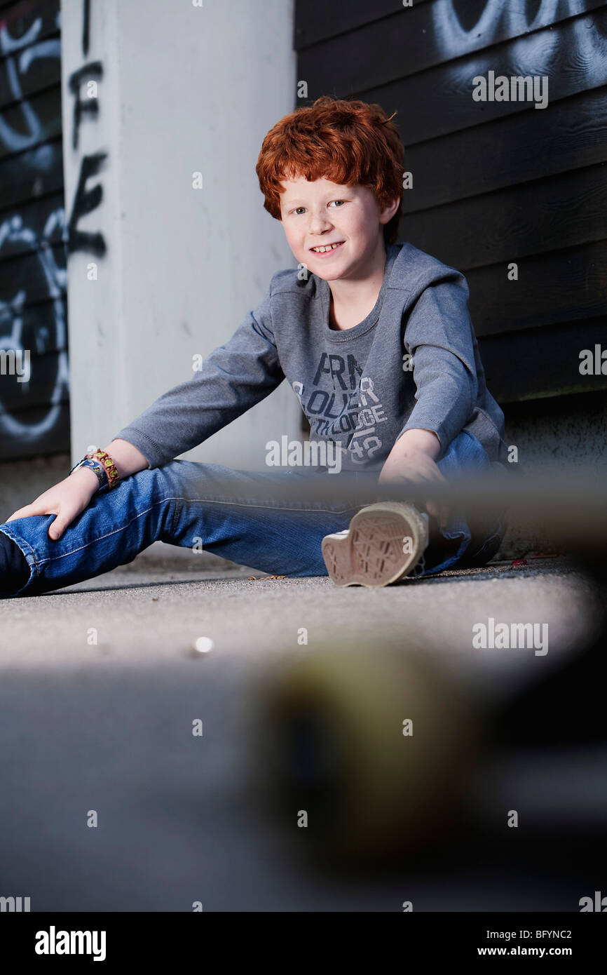 Porträt von roten Haaren Junge saß am Boden Stockfoto