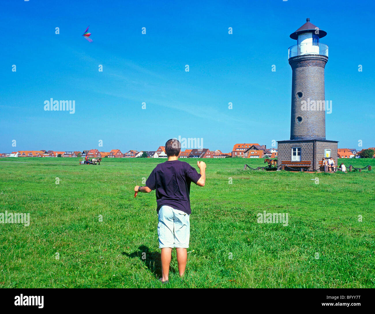 kleiner Junge einen Drachen vor dem Leuchtturm der Insel Juist, Ostfriesland, Niedersachsen, Deutschland Stockfoto