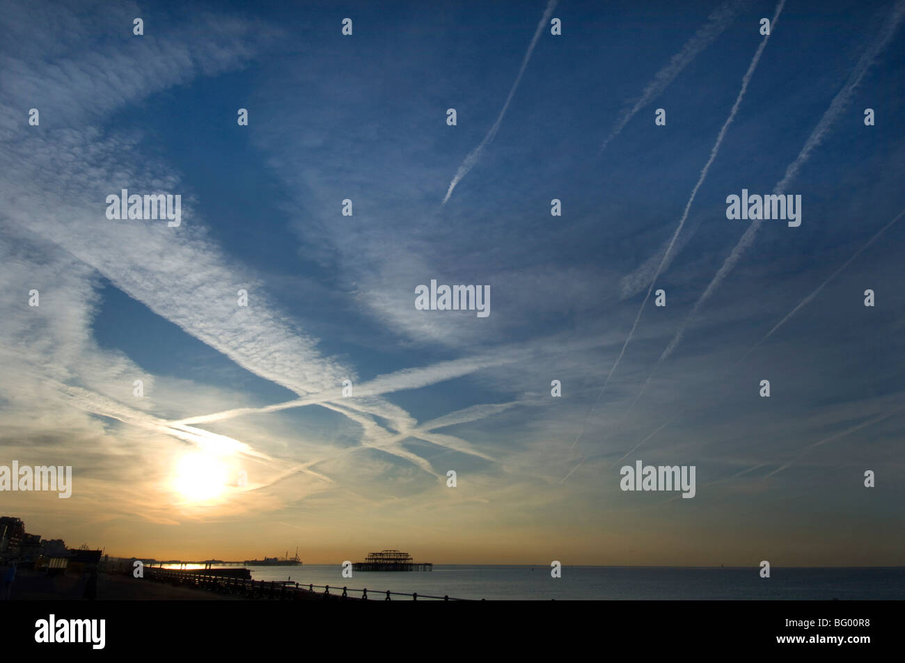 Sonnenaufgang am Brighton Seafront mit Jet-Streifen im Himmel und den West Pier in der Ferne Silhouette. Stockfoto