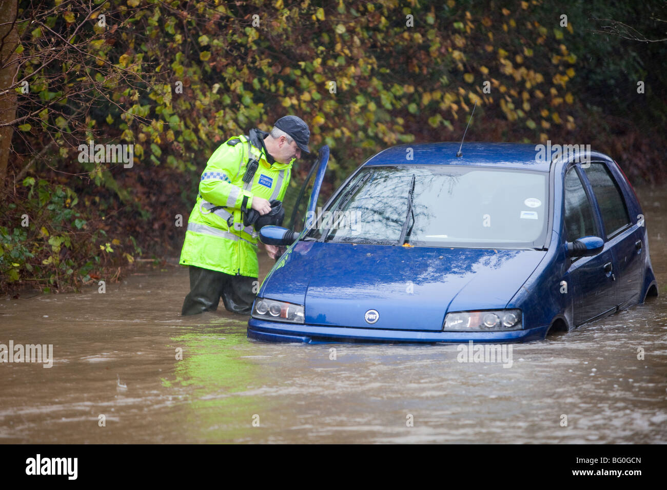 Ein Polizist prüft ein gestrandetes Auto bei den verheerenden Überschwemmungen von November 2009, Cumbria, UK. Stockfoto