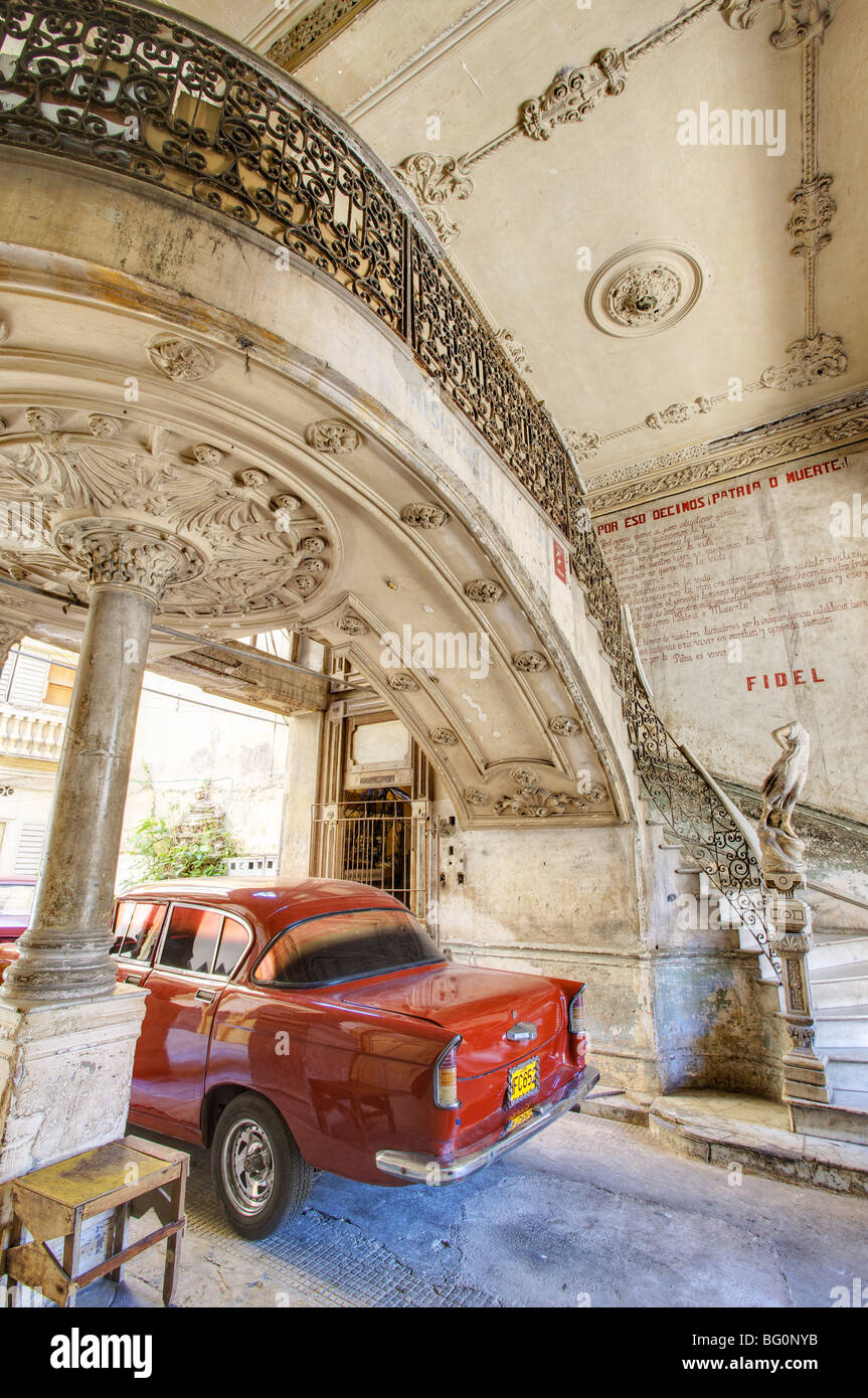 Roter amerikanischer Oldtimer parkten unter verzierten Marmortreppe in baufälligen Wohnhaus, Havanna, Kuba, Westindische Inseln Stockfoto