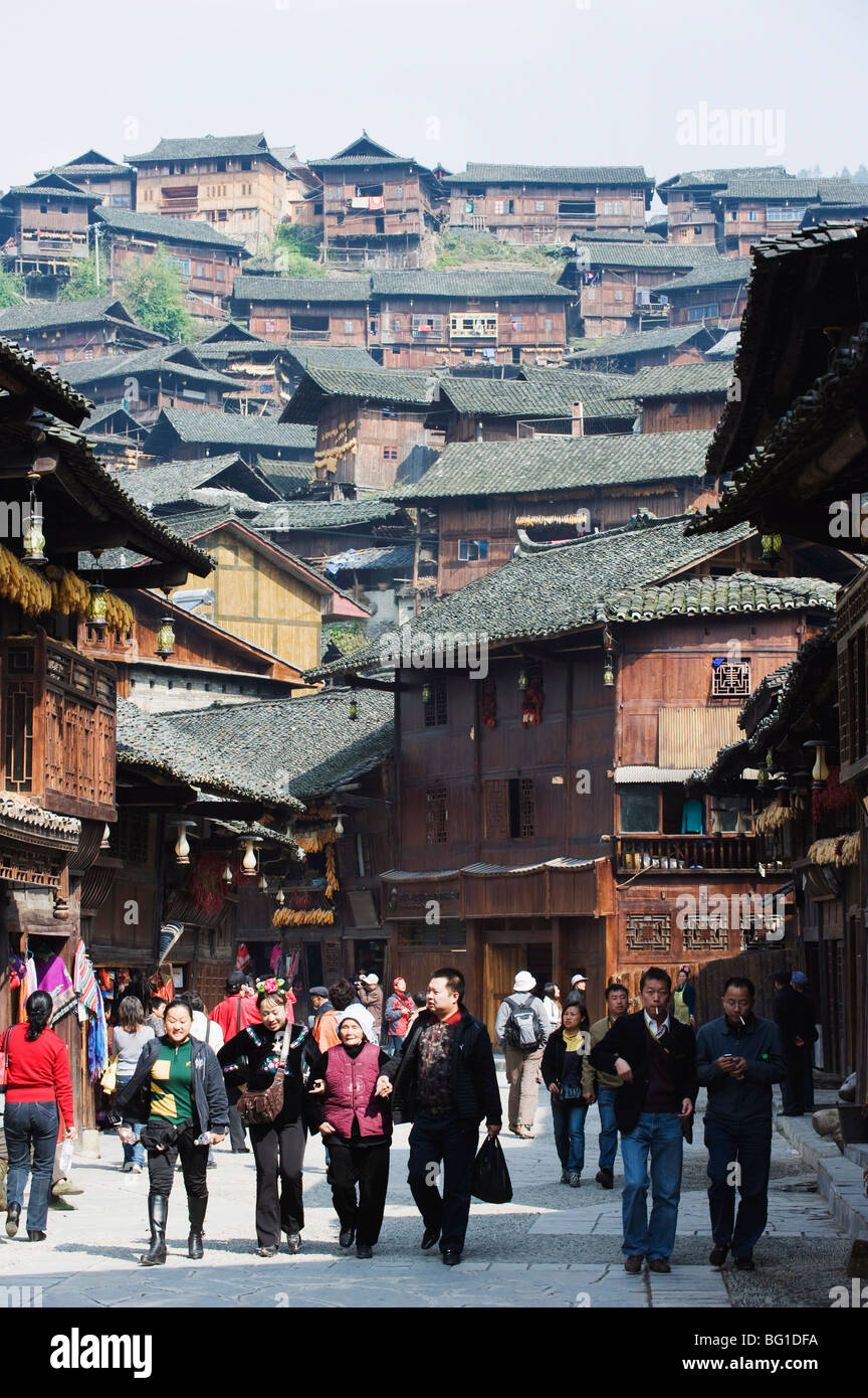 Touristen zu Fuß von Holzhäusern auf den alten Straßen von Xijiang, Provinz Guizhou, China, Asien Stockfoto