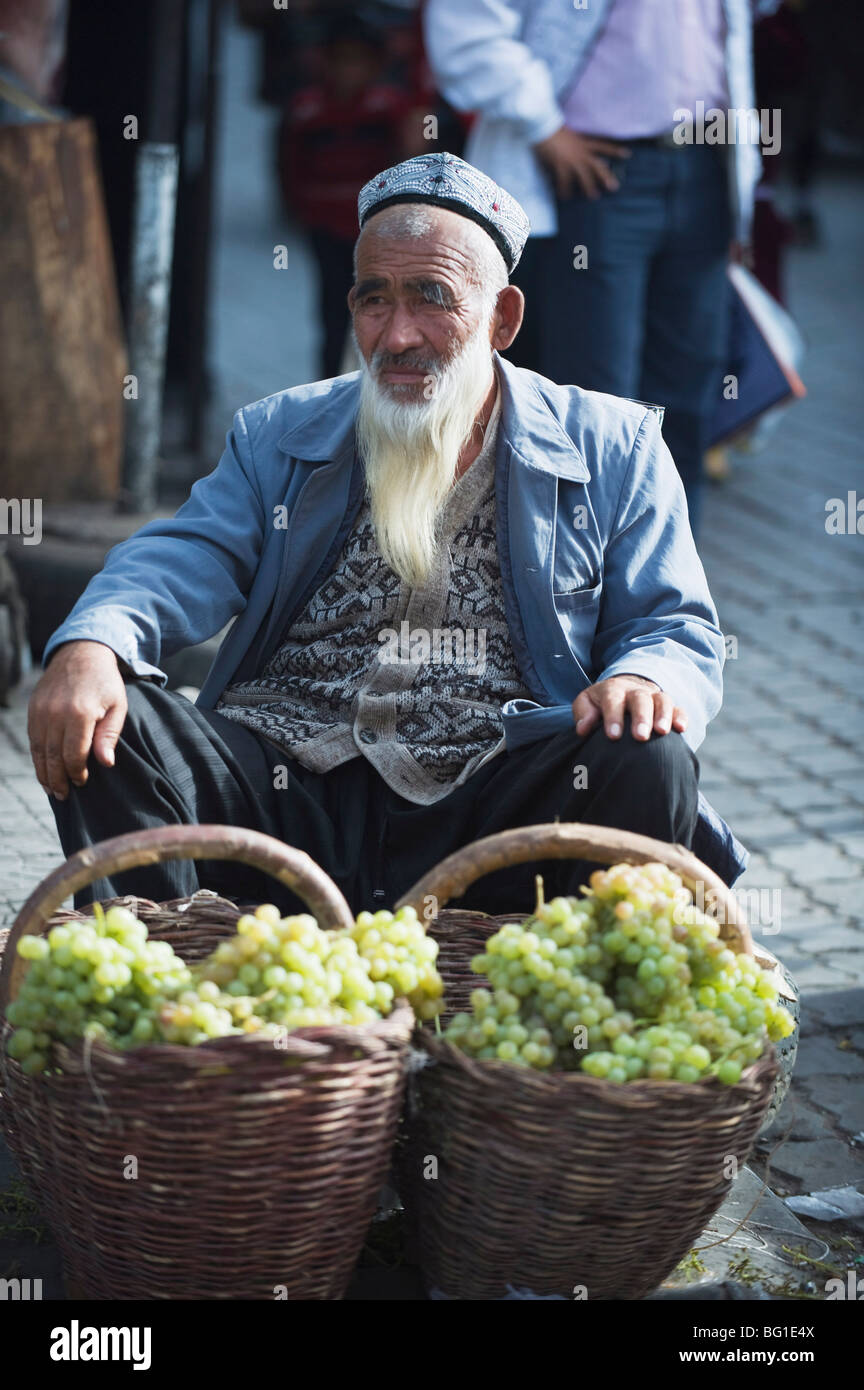 Bärtiger Mann verkaufen Trauben auf dem Sonntagsmarkt, Kashgar (Kashi), Provinz Xinjiang, China, Asien Stockfoto