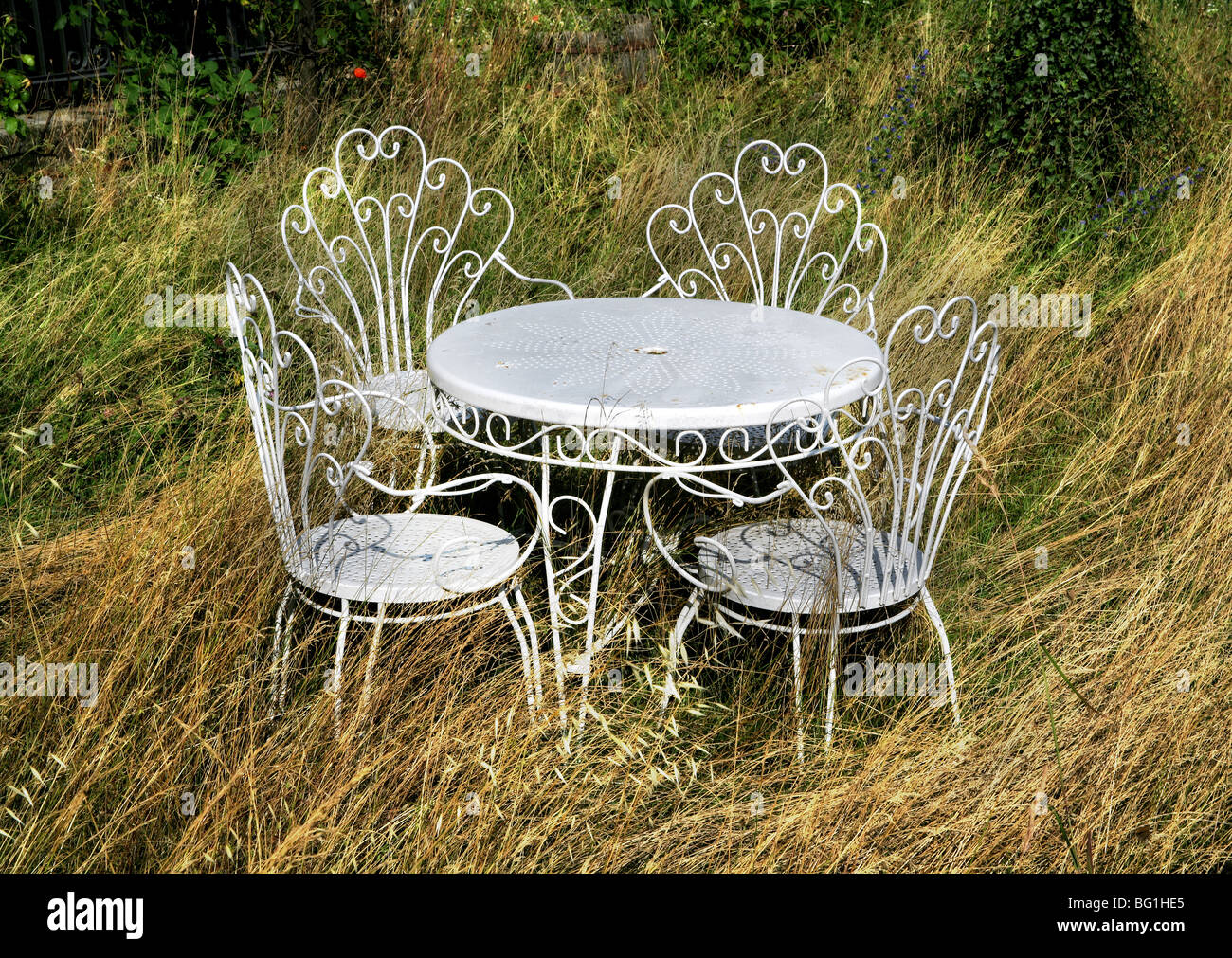 Weißmetall Gartentisch und Stühle im verwilderten Garten Stockfoto