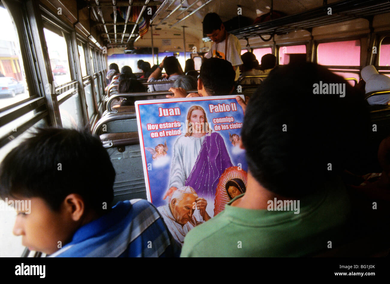 Zwei junge Männer in einem öffentlichen Bus in der Nähe von Antigua, Guatemala halten ein Plakat, das enthält Bilder von Jesus und Papst John Paul Stockfoto