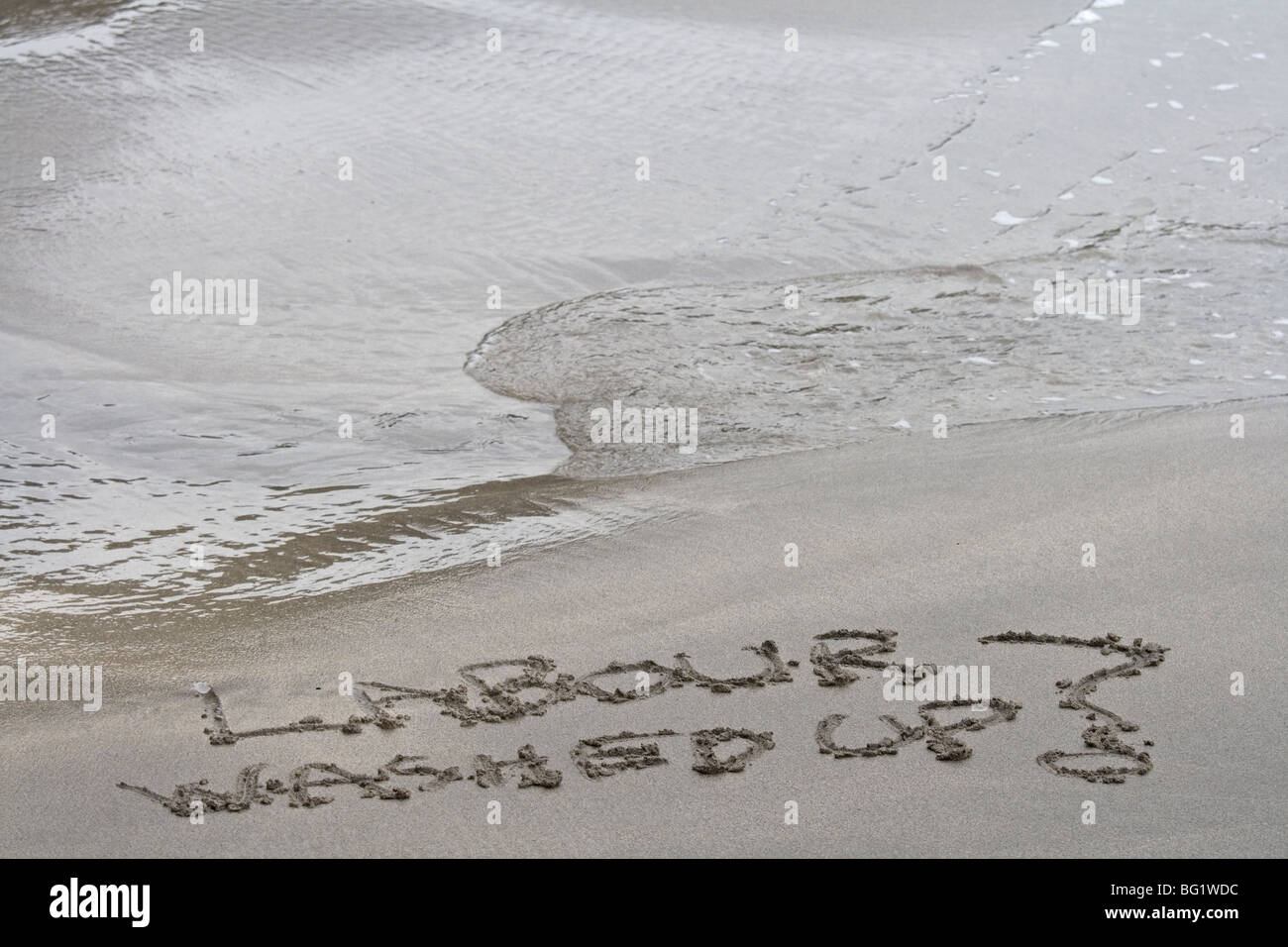 Die Arbeit, die im Sand mit einer Wende aufgeschriebenem ist. Symbolisch Stockfoto