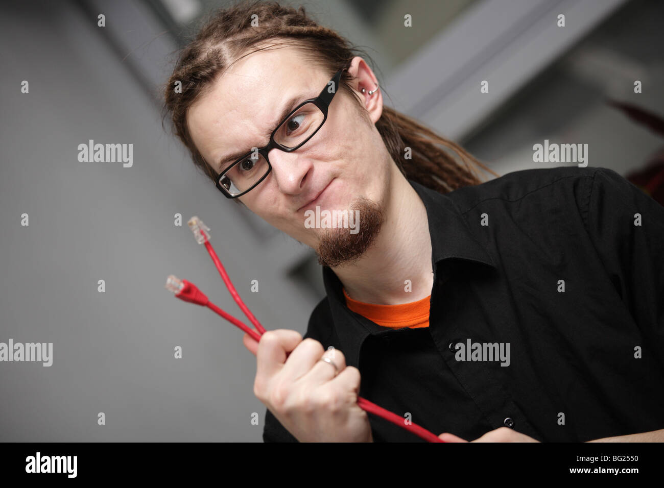 entmutigt junger Mann schaut eine rote Patchkabel Stockfoto