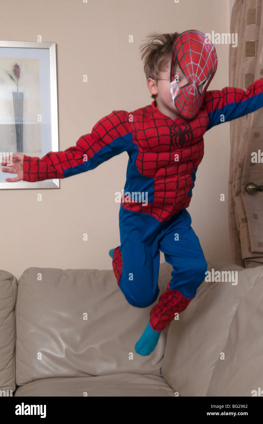 3 Jahre alter Junge in spiderman-Anzug und Maske gekleidet und auf Möbel springt. Stockfoto