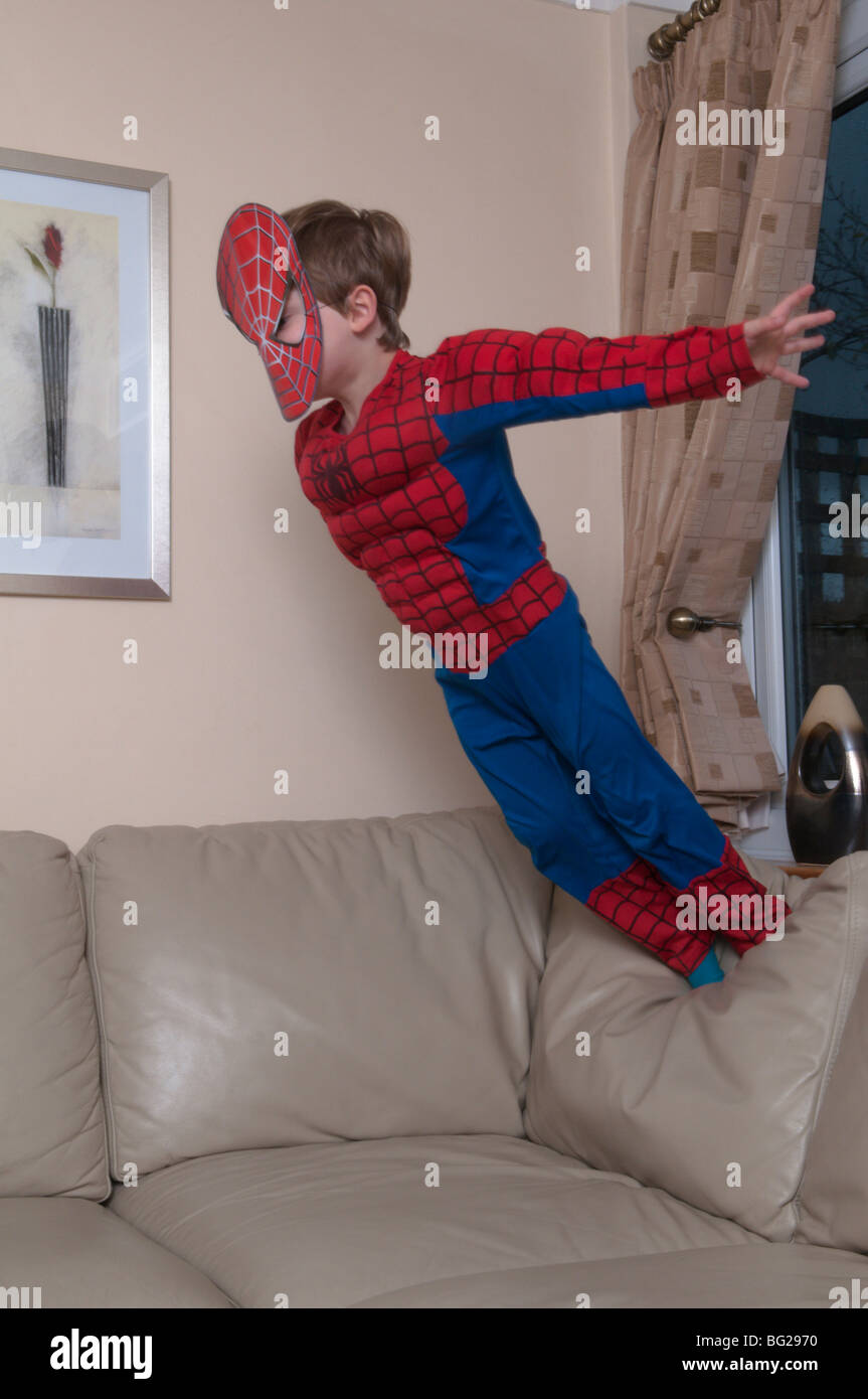 3 Jahre alter Junge in spiderman-Anzug und Maske gekleidet und auf Möbel springt. Stockfoto