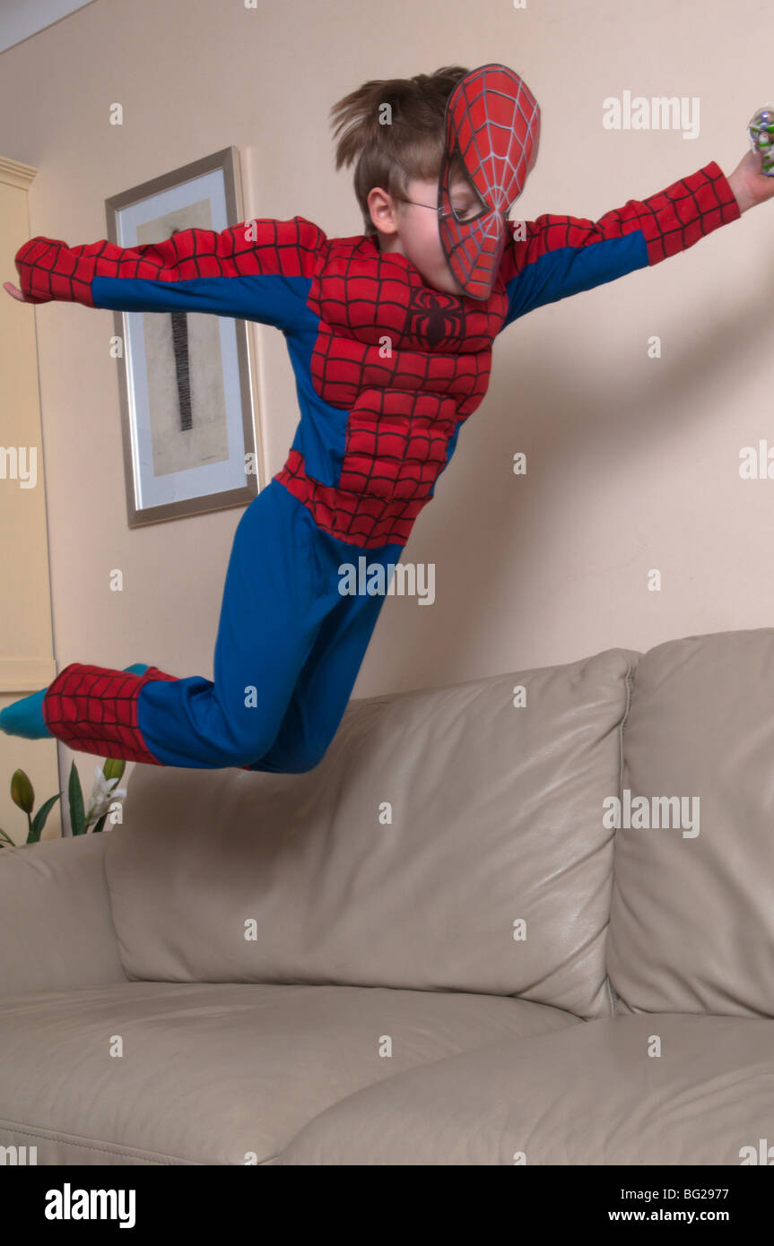 3 Jahre alter Junge in spiderman-Anzug und Maske gekleidet und auf Möbel springt. Stockfoto