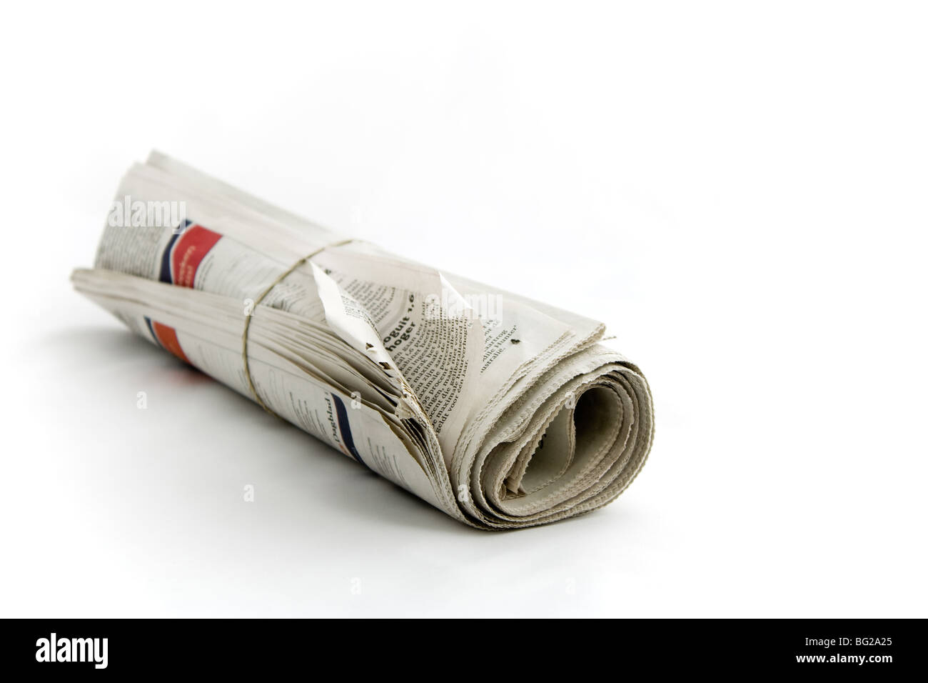 Zeitung mit Gummiband auf einfachen Hintergrund gedreht mit Fokus auf Vordergrund gerollt Stockfoto