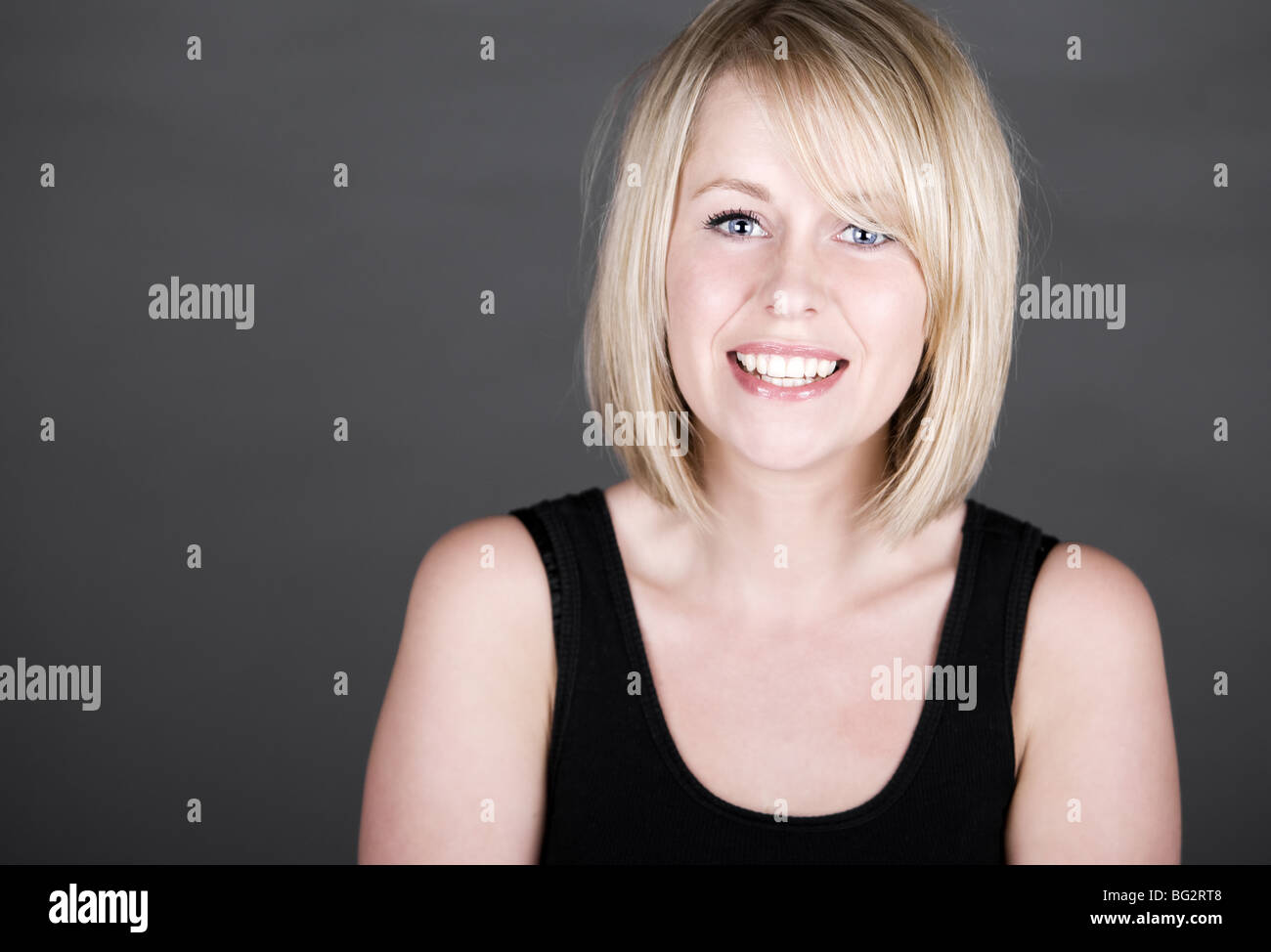 Schuss von einem schönen Lächeln auf den Lippen Blonde Mädchen vor grauem Hintergrund Stockfoto