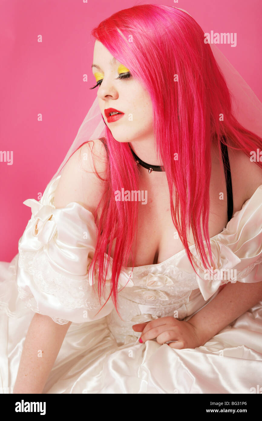 Alternative aussehendes Mädchen mit leuchtend roten Haaren trägt ein weißes Brautkleid und Nieten Halsband. Stockfoto