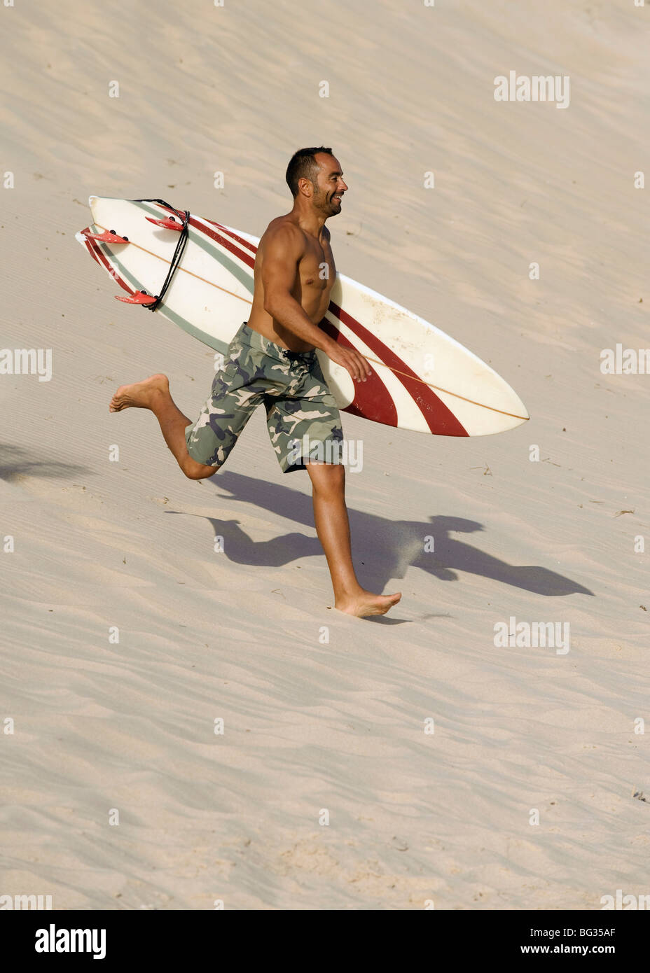 Mann läuft mit einem Surfbrett am Strand Stockfoto