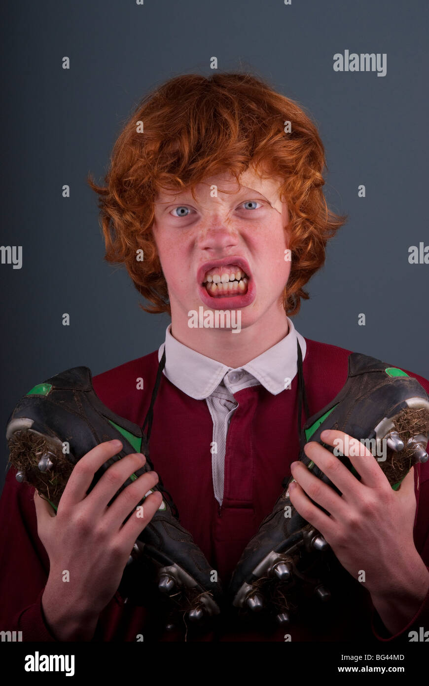 Ginger behaarte Teenager mit ein paar Rugby-Stiefel ringsum seinen Ansatz Stockfoto