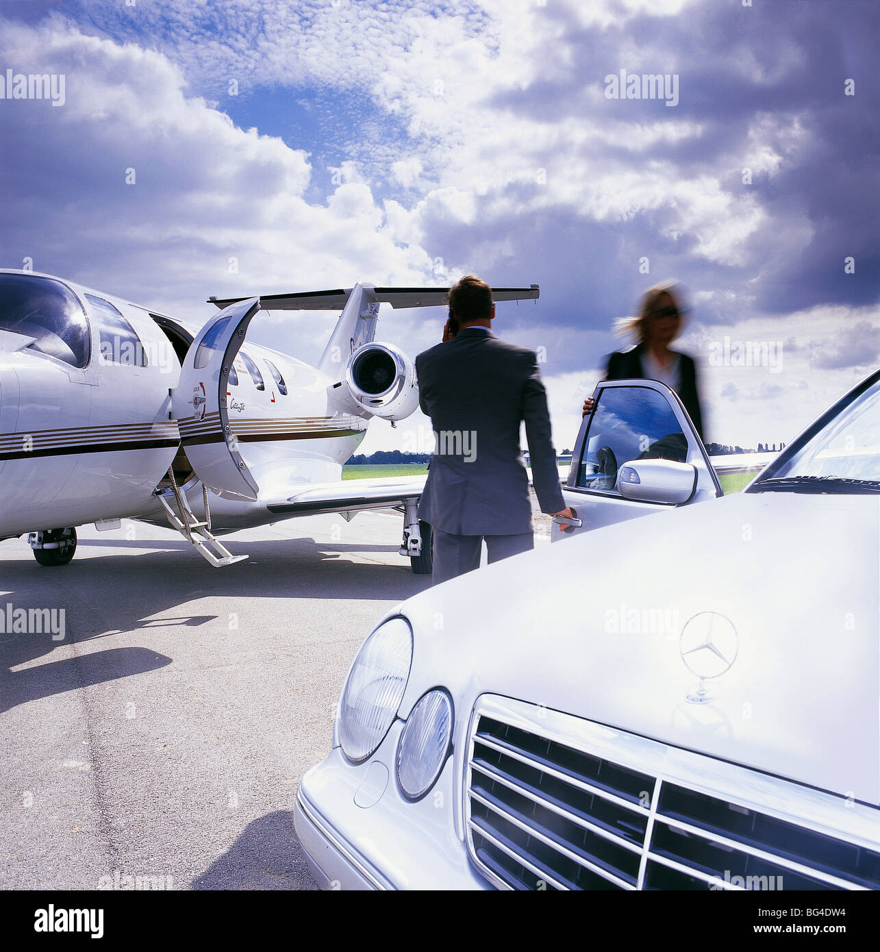 Weibliche Führungskraft Chauffeur auf Asphalt neben ihrem Privat-Jet, eine dramatische Himmel erfüllt Stockfoto