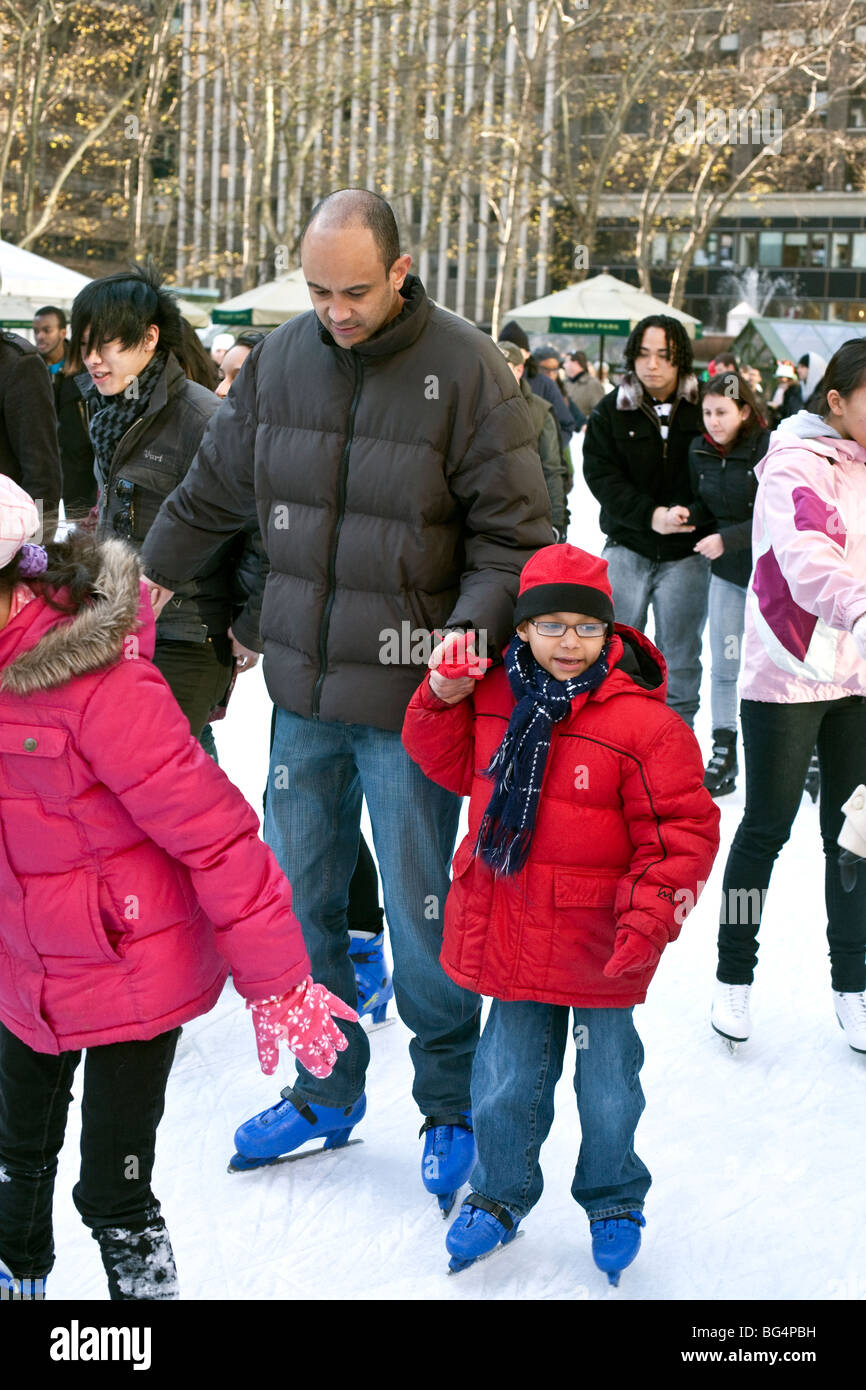 kleines Mädchen verlor in Wunder klammerte sich fest an Papas Hand, wie sie in multikulturellen Publikum skating Teich im Bryant Park NYC skate Stockfoto