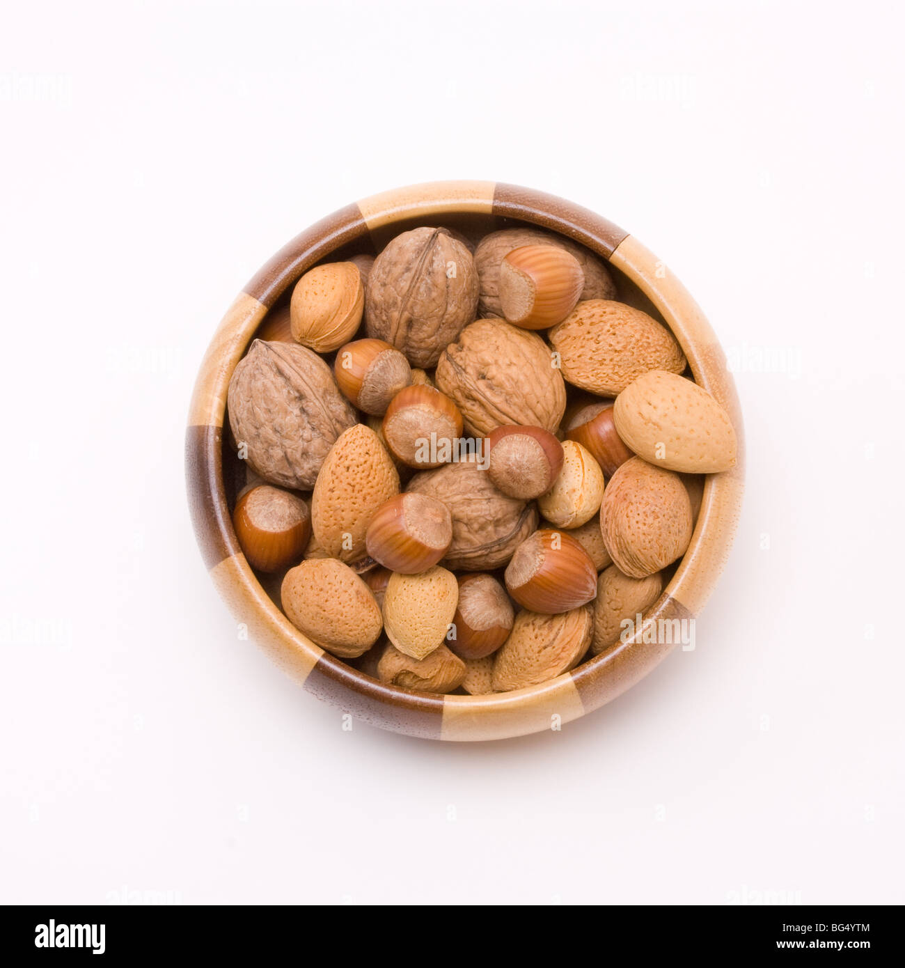 Holzschale mit gemischten Nüssen in ihren Schalen, Haselnüsse, Walnüsse und Mandeln gefüllt. Stockfoto