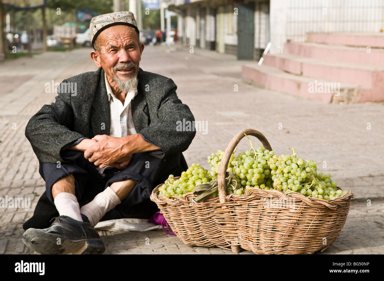 Ein Alter Mann in uigurischen Verkauf von Trauben in der alten Stadt Kashgar. Stockfoto