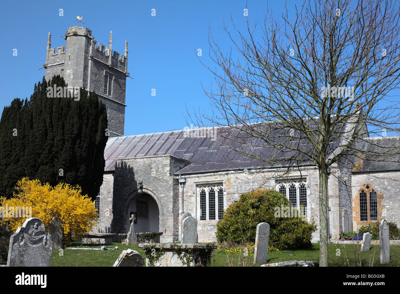 Traditionelle englische Kirche mit Friedhof, Grabsteine und Bäumen an einem sonnigen Tag Stockfoto