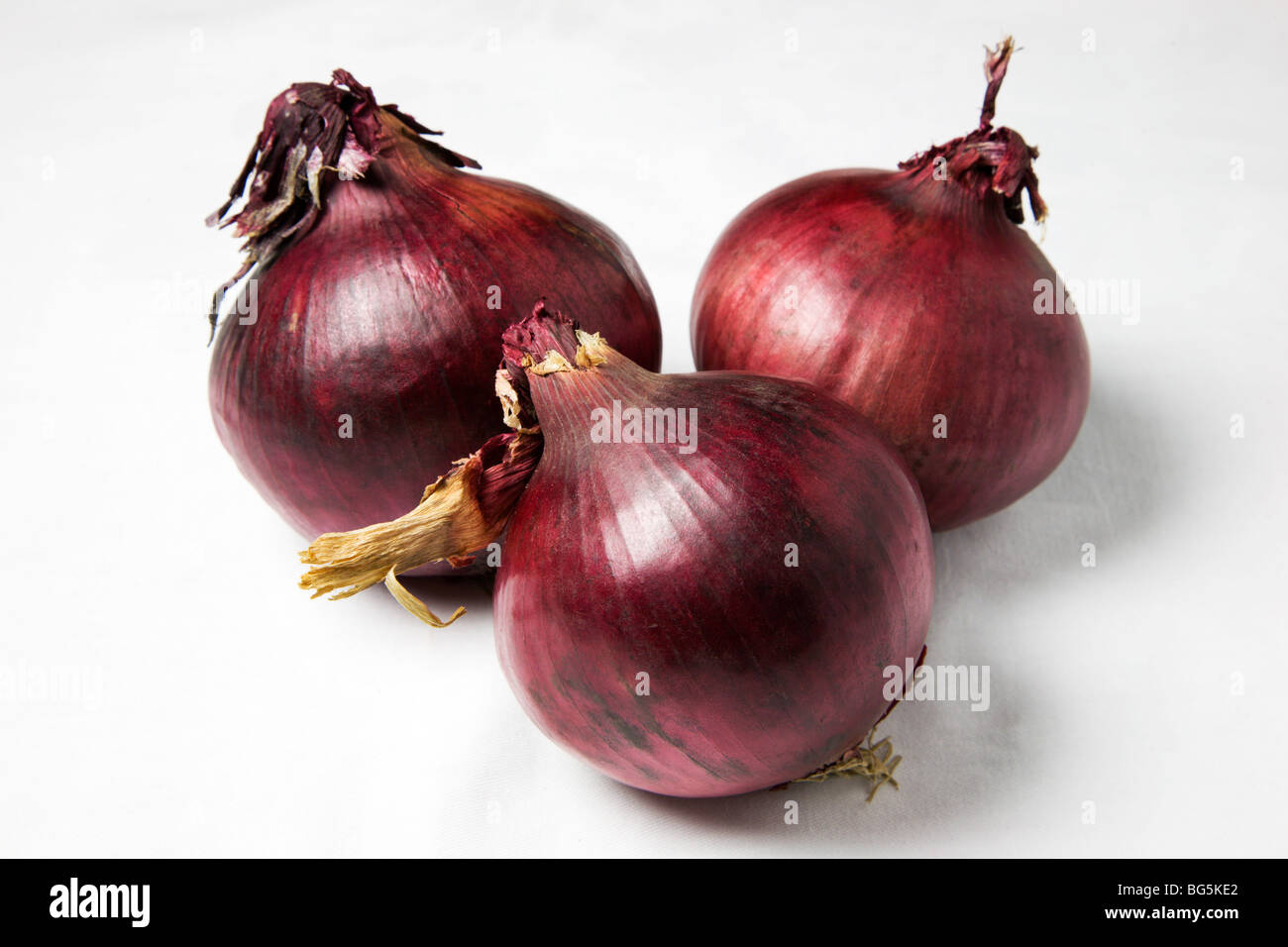 Drei rote Zwiebeln und einen weißen Hintergrund Stockfoto