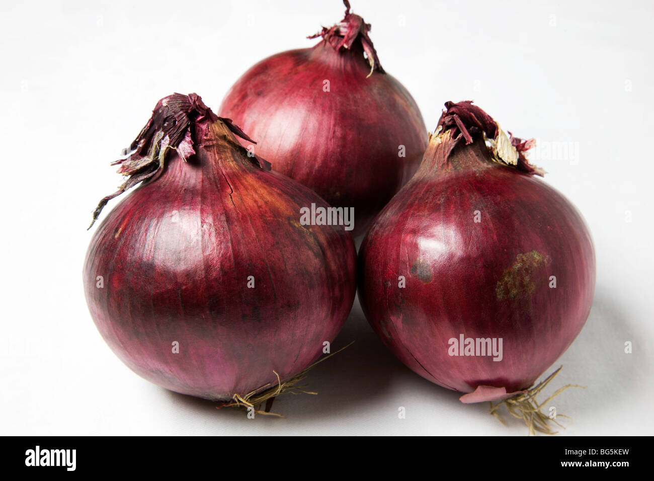 Drei rote Zwiebeln und einen weißen Hintergrund Stockfoto
