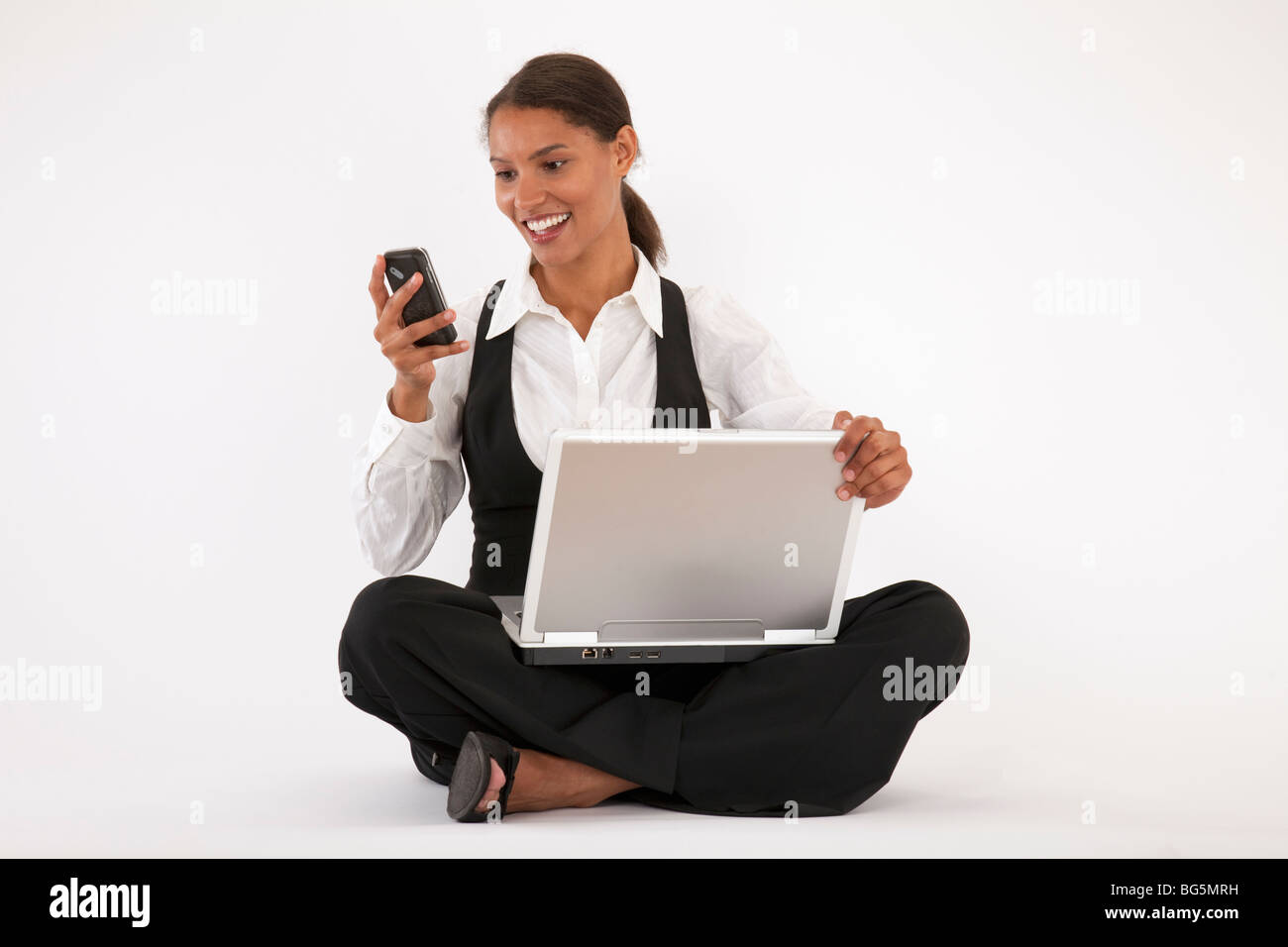 Junge Frau am Boden mit Laptop und Handy. Horizontal-Format. Stockfoto