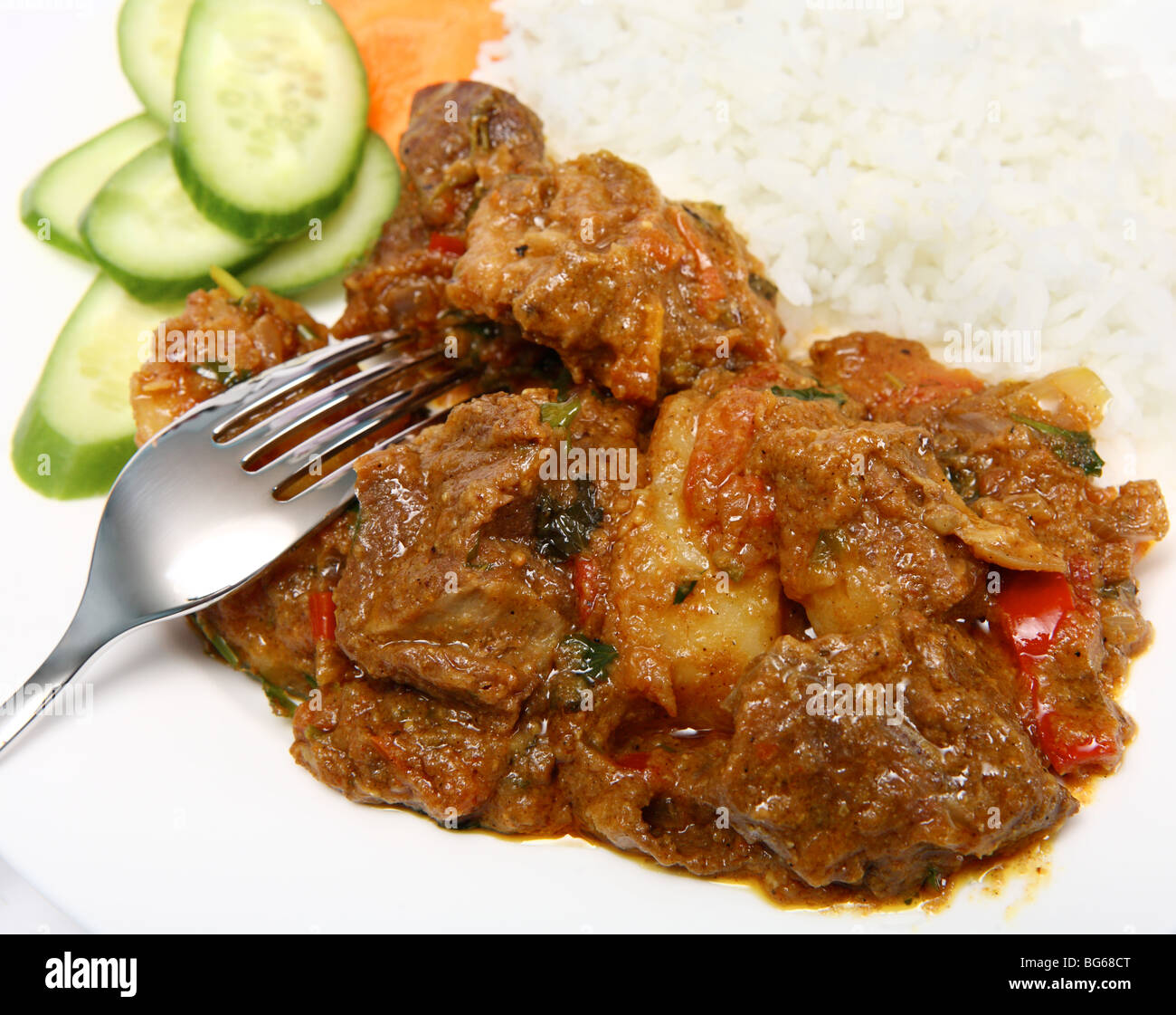 Ein Teller mit traditionellen Mutton Vindaloo, serviert mit Reis und Salat aus Gurke und Karotte. Stockfoto
