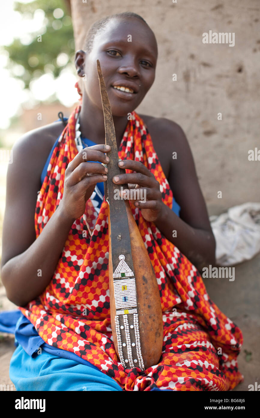 Eine Massai-Frau in traditioneller Kleidung hält ein Milchkännchen, geschmückt mit Perlen in Kilombero Dorf, Manyara Region, Tansania. Stockfoto