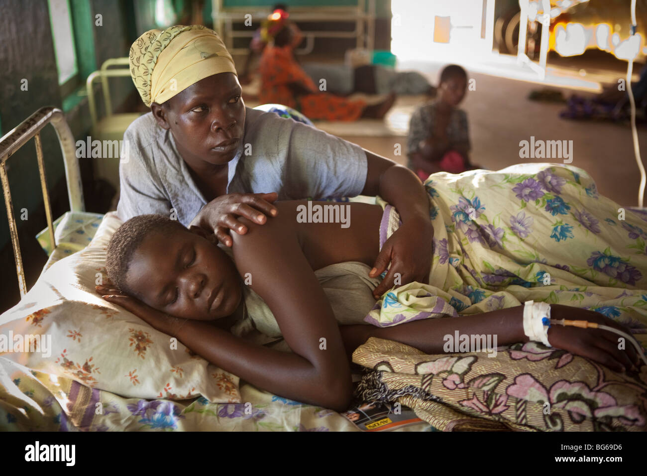 Eine Mutter kümmert sich um ihre Tochter, die an Malaria in einem Krankenhaus in Amuria, Uganda. Stockfoto