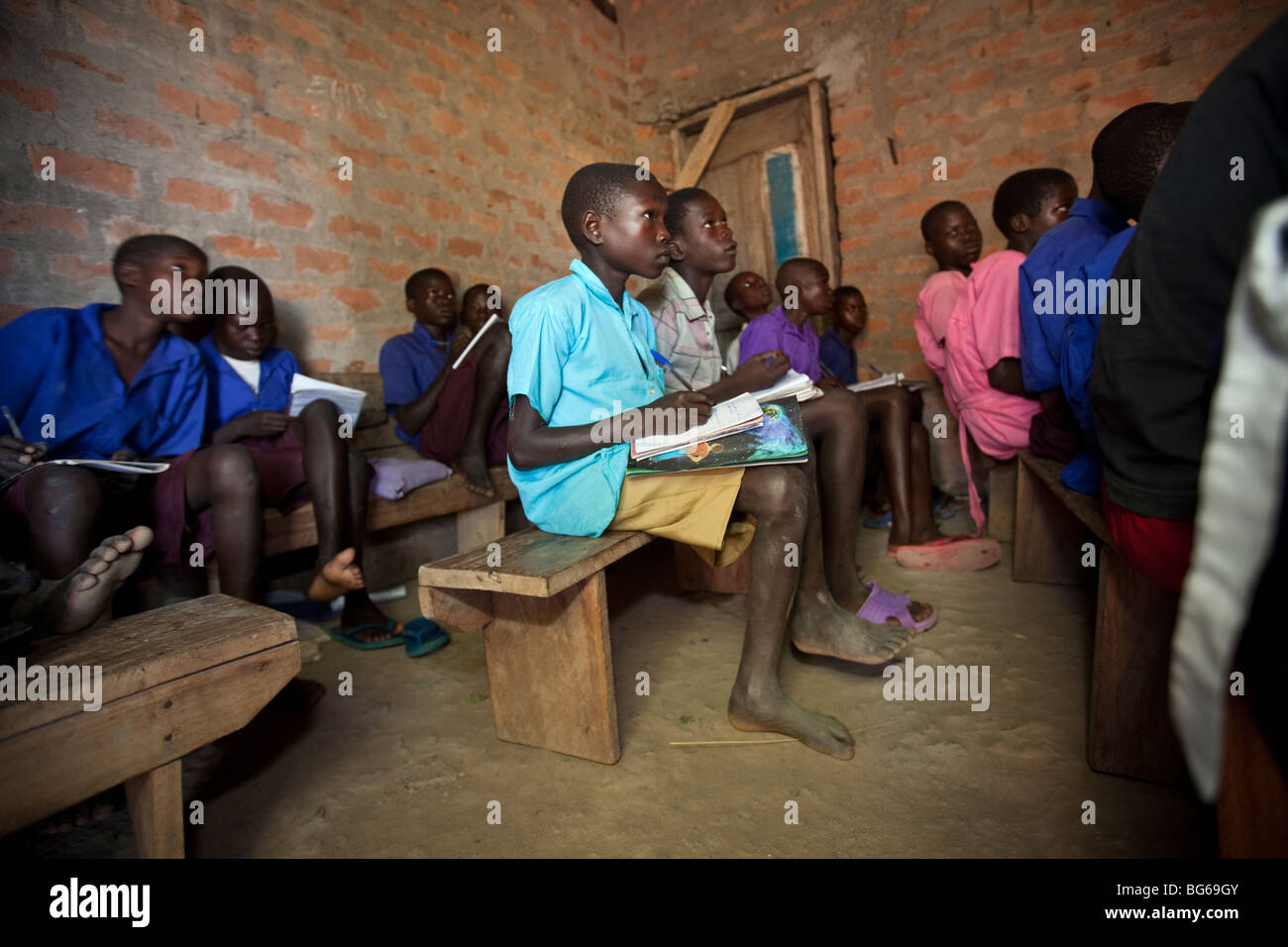 Kinder im Grundschulalter lernen in einem dunklen Klassenzimmer ohne Schreibtische in Amuria, Osten Ugandas. Stockfoto