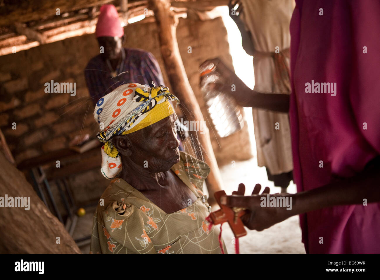 Eine Frau erhält eine Prise von Weihwasser in einer katholischen Kirche in Amuria Bezirk, Teso Subregion, Uganda, Ostafrika. Stockfoto