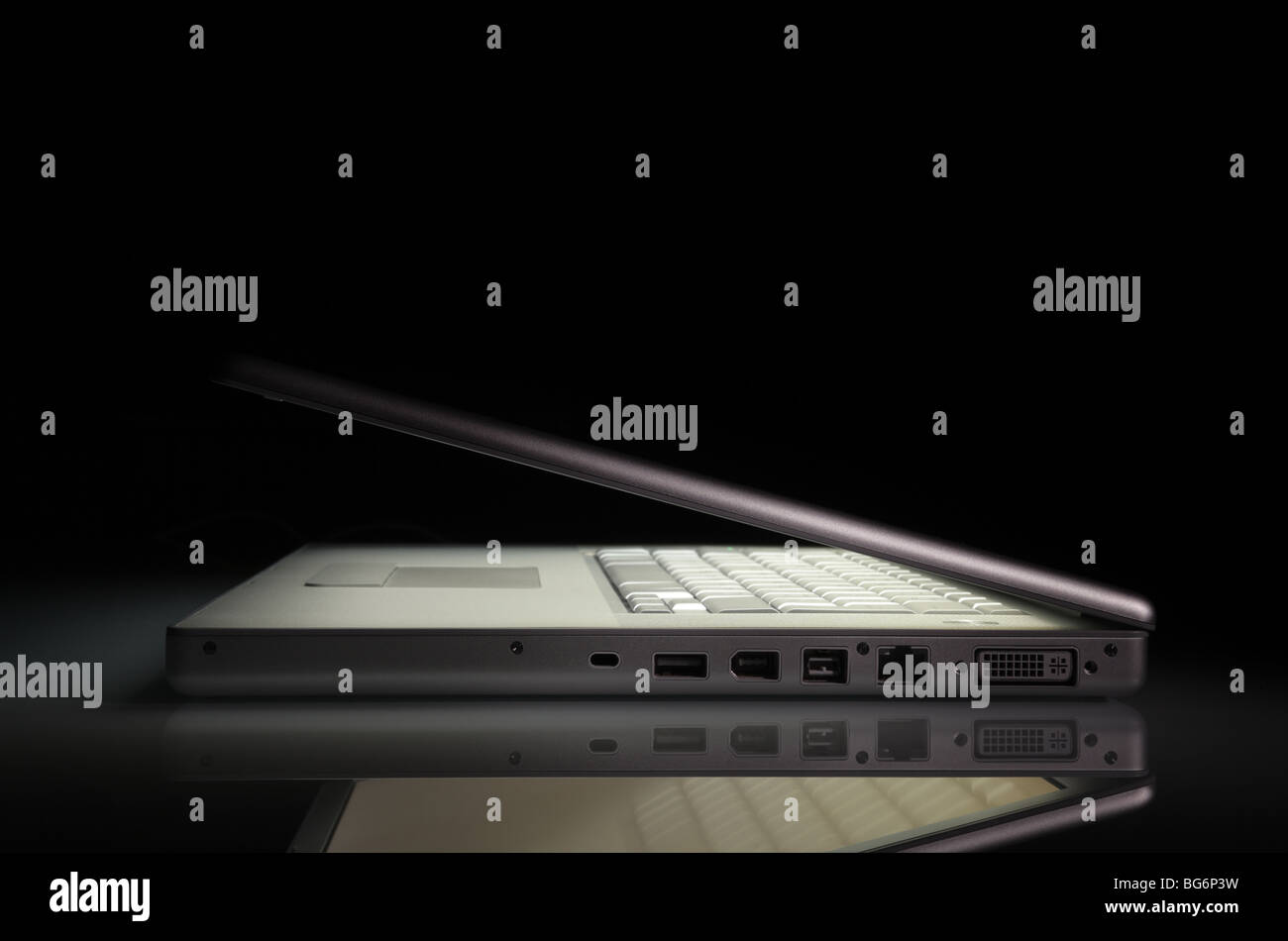 Laptop Notebook mit einem leuchtenden Bildschirm auf eine Reflexionsfläche, auf einem schwarzen Hintergrund mit textfreiraum Silber. Seitenansicht. Stockfoto