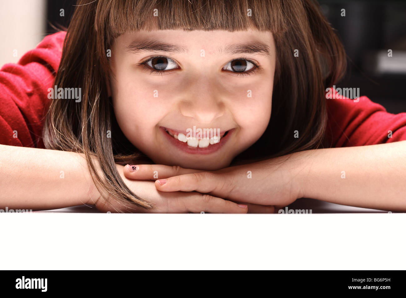 Lachende Mädchen 9 Jahre alt hinter einen weißen Tisch Stockfoto