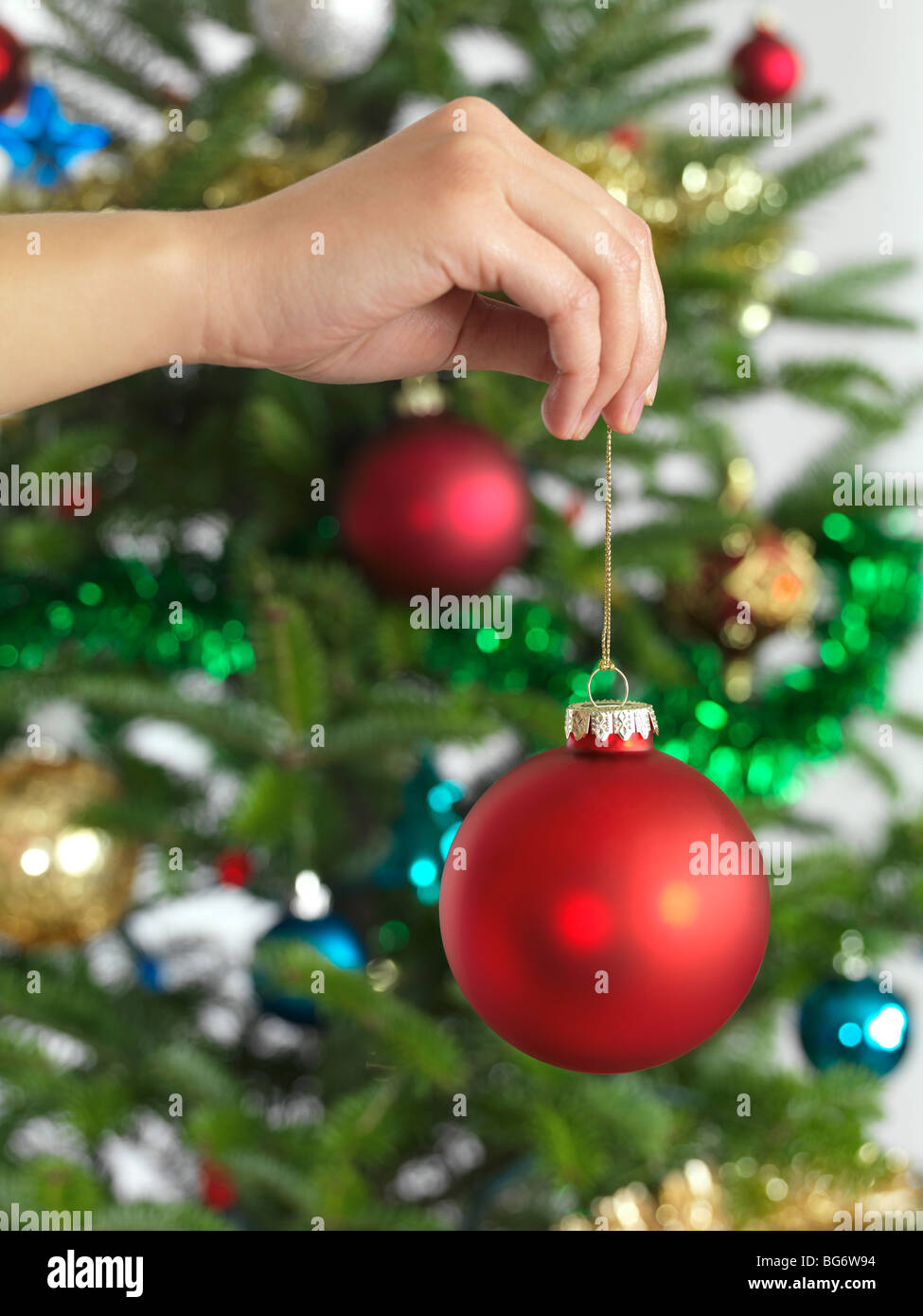 Frau mit Christbaumschmuck in eine Hand einen Weihnachtsbaum zu verzieren Stockfoto