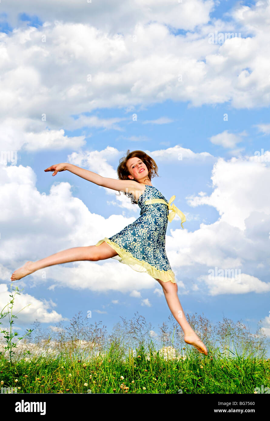 Junge Teenager-Mädchen springen in Sommerwiese inmitten von Wildblumen Stockfoto