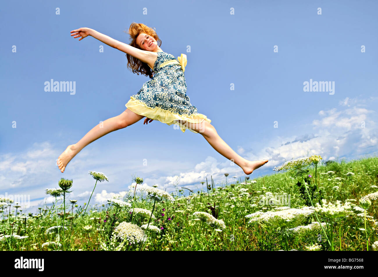 Junge Teenager-Mädchen springen in Sommerwiese inmitten von Wildblumen Stockfoto